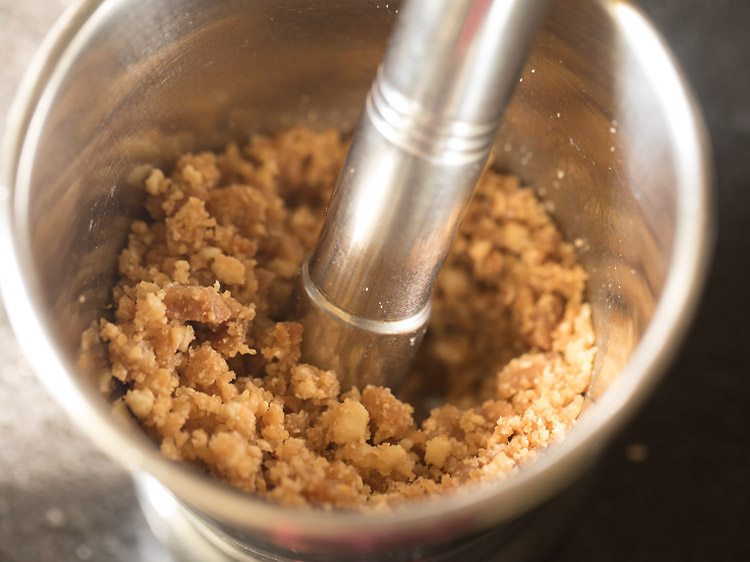 crushing the praline pieces with a pestle to make praline ice cream