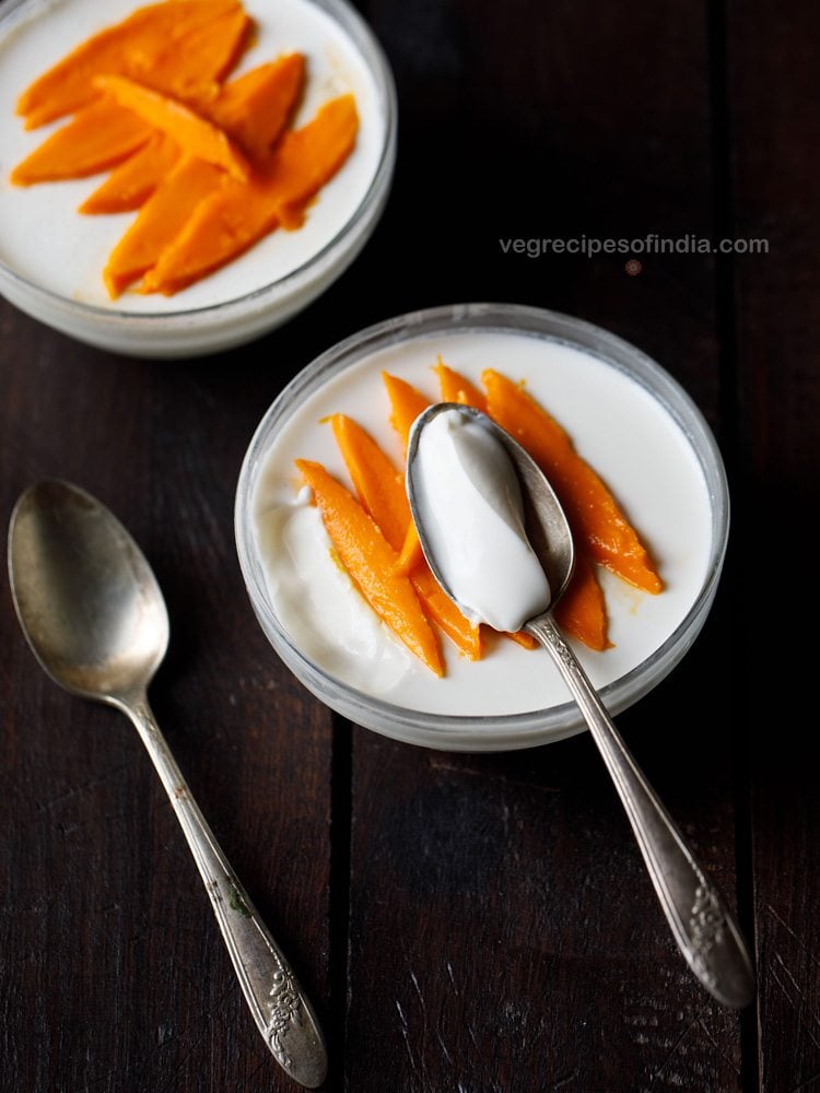 overhead shot of classic panna cotta recipe made with no gelatin in a clear bowl and garnished with mango slices