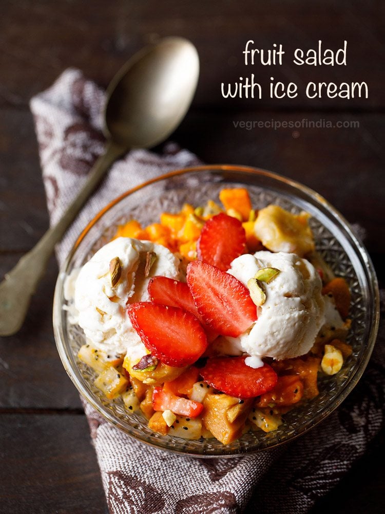 fruit salad with ice cream and nuts served in a glass bowl.