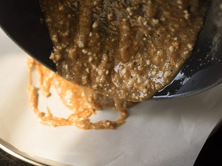 pouring praline mixture on a plate lined with butter paper 