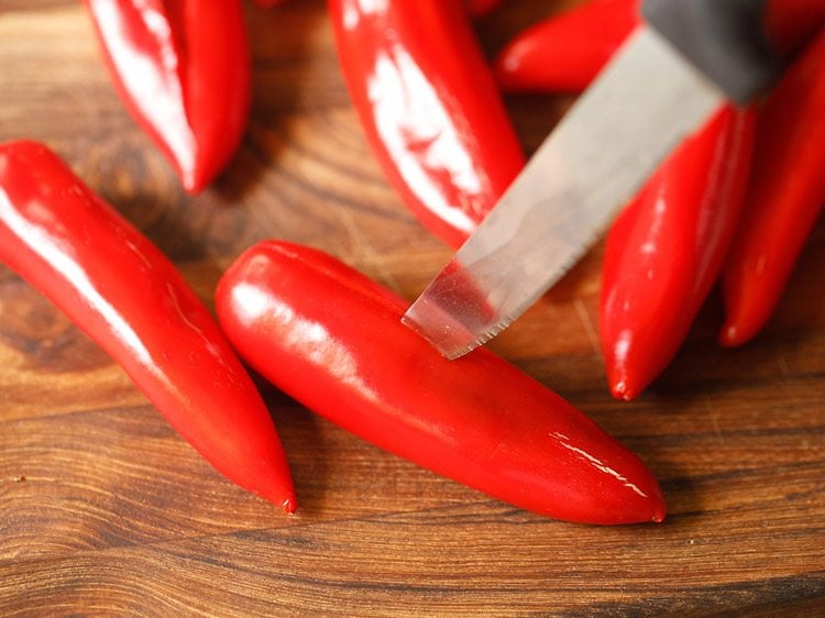 removing crowns of red chilies and slitting them 