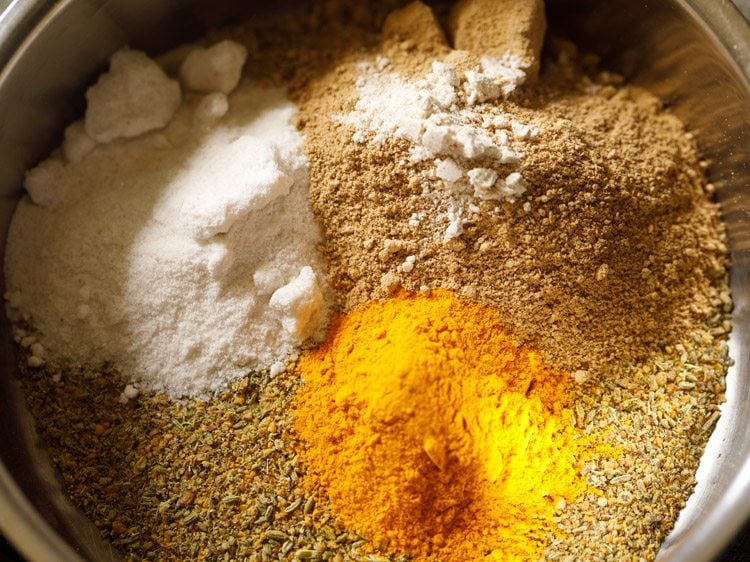 adding dried mango powder, turmeric powder, asafoetida and salt to the powdered spices 