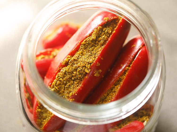placing stuffed red chilies in a glass jar