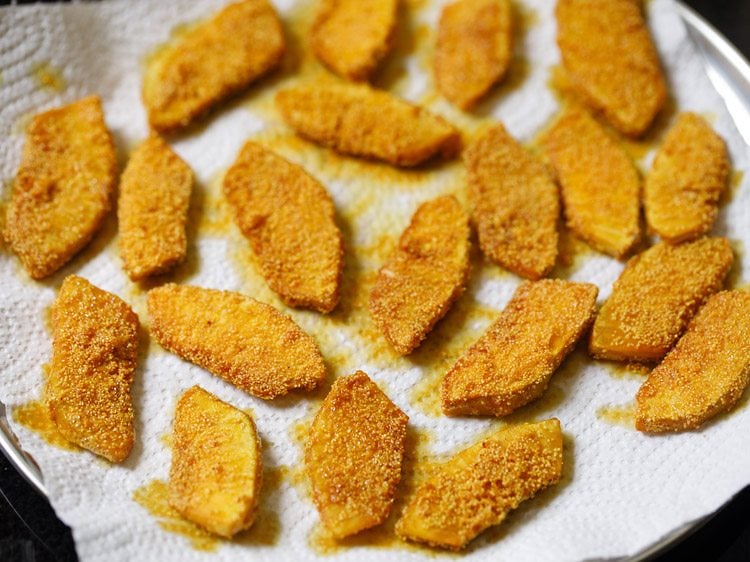 fried breadfruit slices placed on kitchen paper towel. 