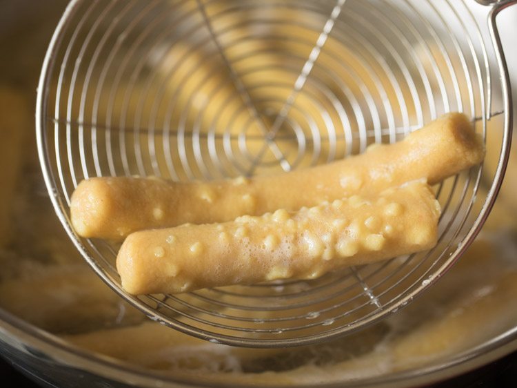 removing cooked gatte from water with a slotted spoon. 