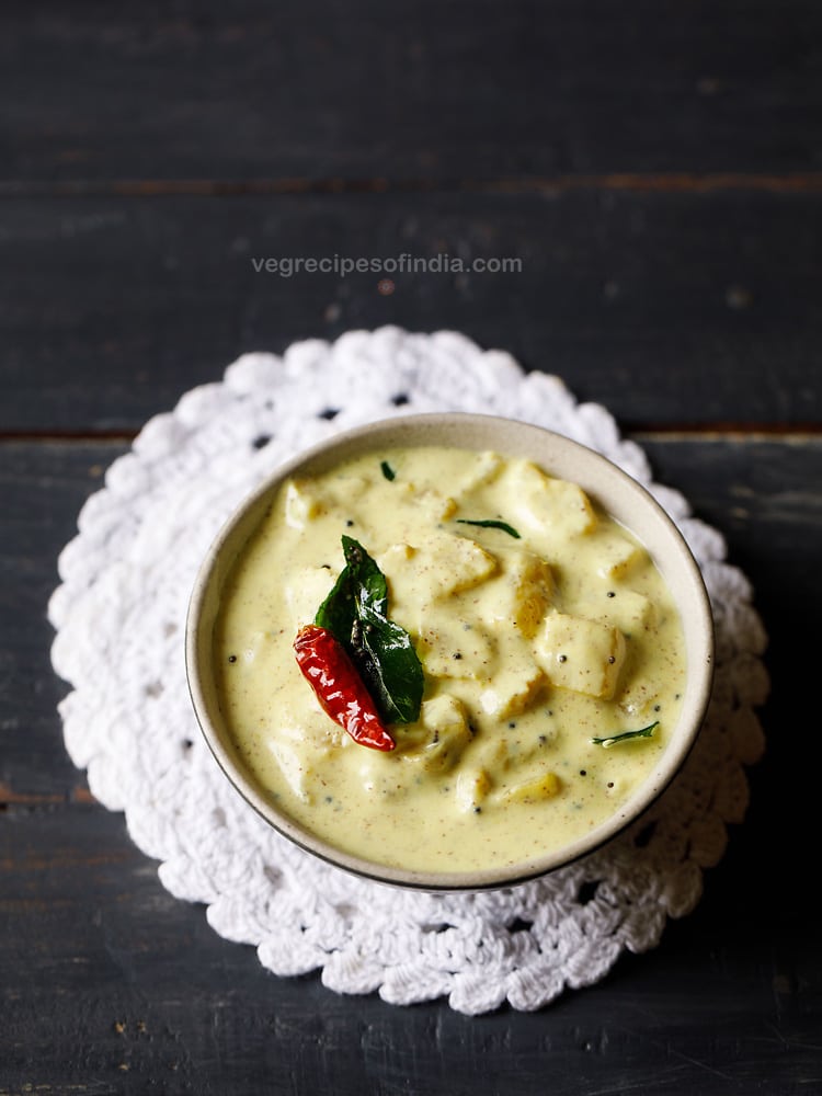 Kerala pineapple pachadi in a small bowl on a white crocheted doily garnished with tempered chile and curry leaf.