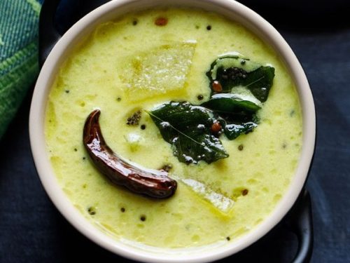 mor kulambu served in a black bowl.