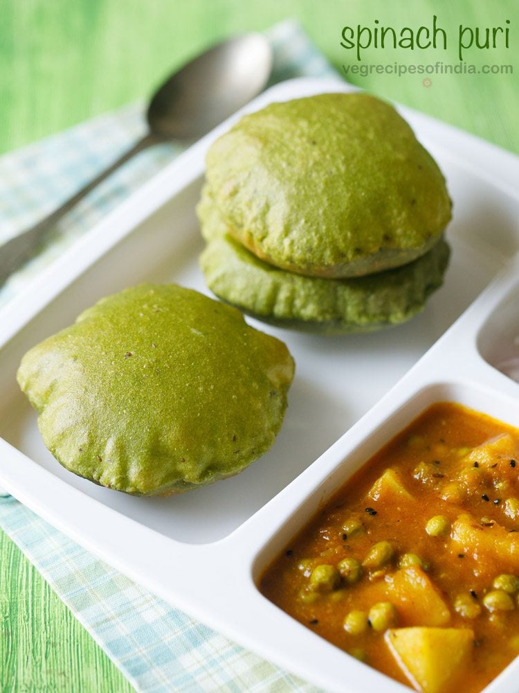 palak puri served in a sectioned platter with aloo matar, onions on the side and a spoon kept on the top in the background and text layover.