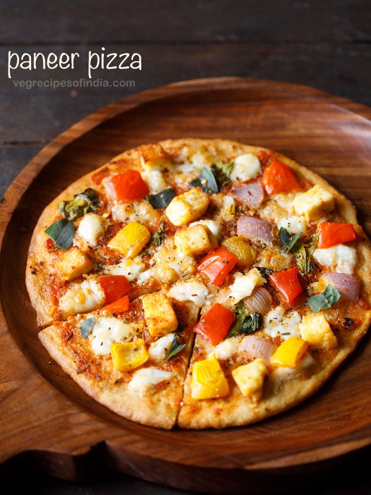 paneer pizza cut into a wedge and served on a wooden pizza board. 