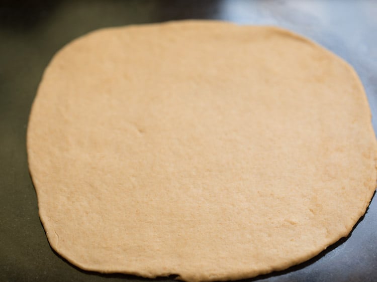 pizza dough part rolled to a medium thick base. 