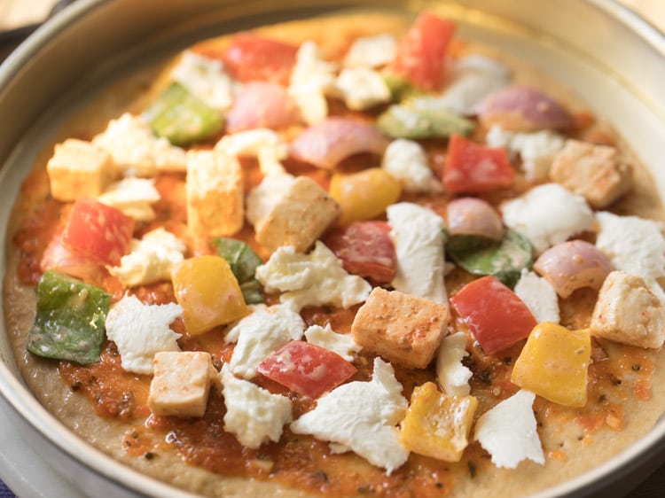marinated vegetables and paneer added on top of the pizza base. 
