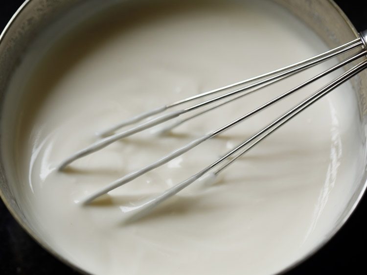 curd in a mixing bowl with a whisk.