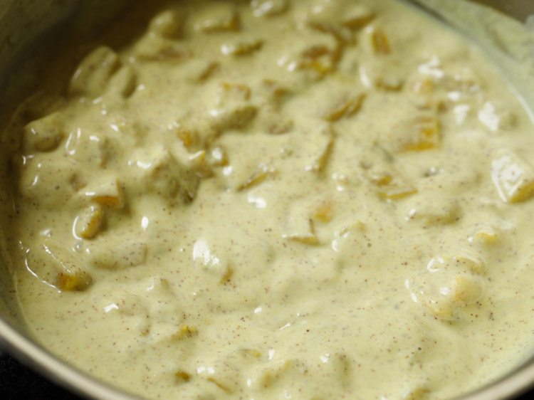 stirring the pineapple pachadi to incorporate the curd.