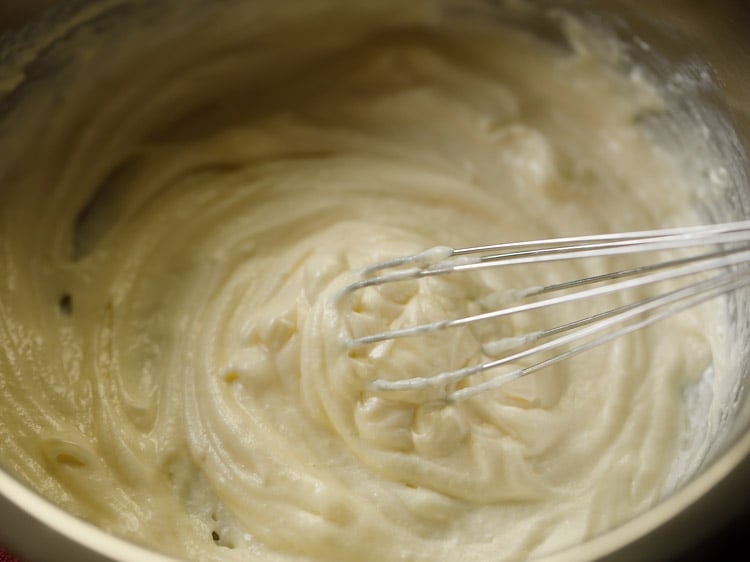 whisking curd with creamed ghee for making badusha. 