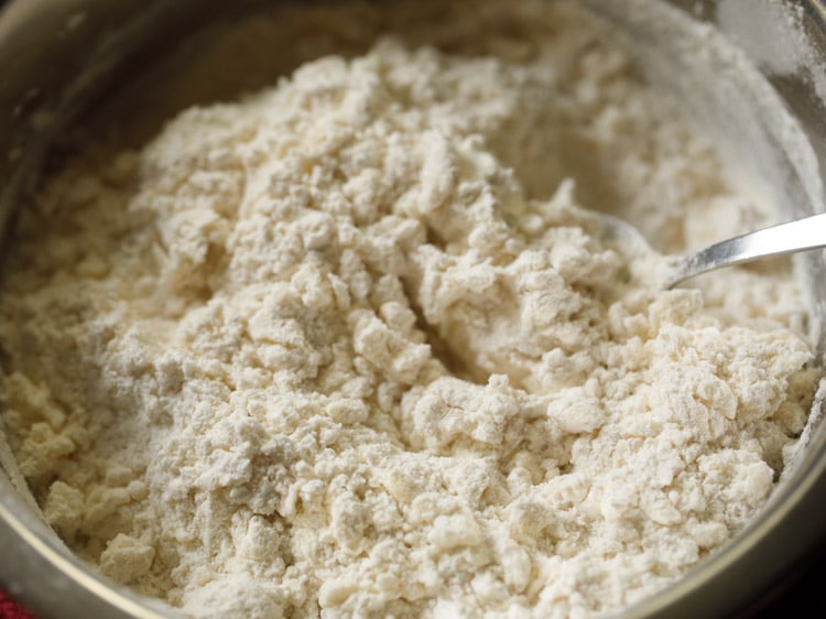 mixing flour with creamed mixture with a spoon for making badusha. 