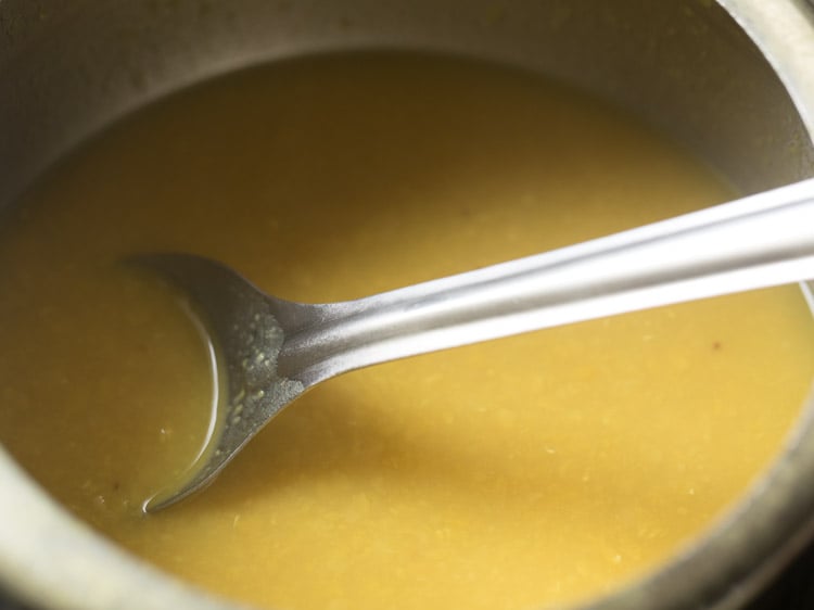 mashing the cooked dal with a spoon. 