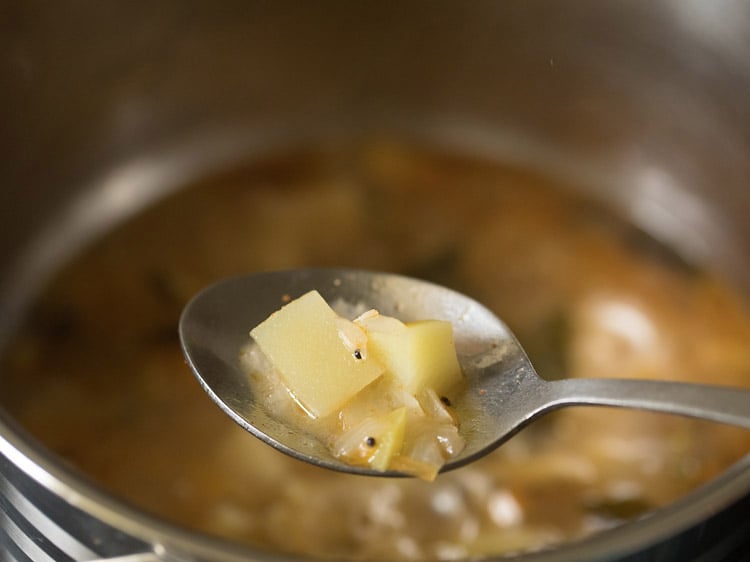 cooking the raw mango cubes in the pan. 