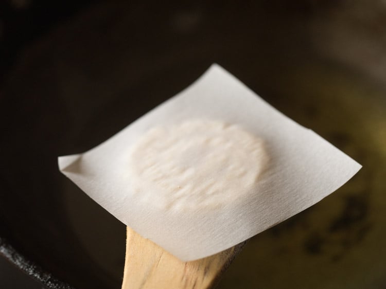 turn over the butter paper with murukku onto a wooden spatula. 
