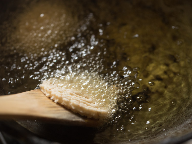 sliding murukku from the wooden spatula in the hot oil. 