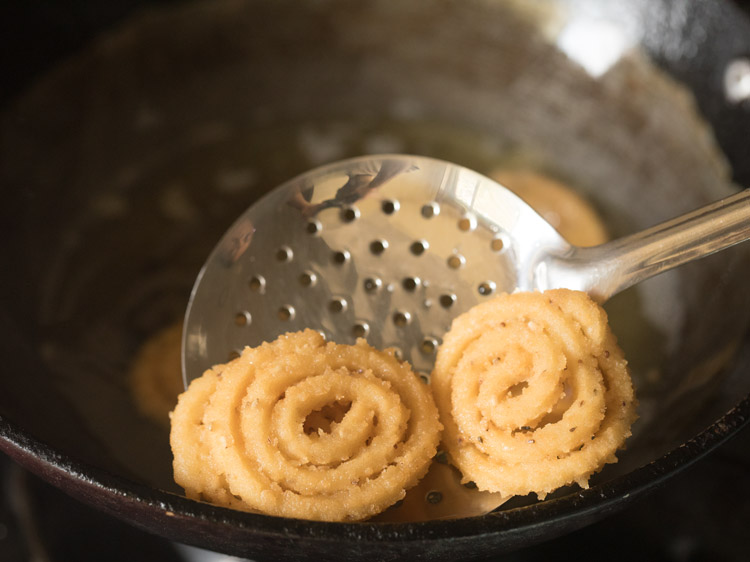 removing fried murukku with slotted spoon