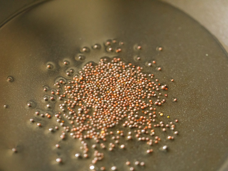 mustard seeds added to hot sesame oil in pan. 