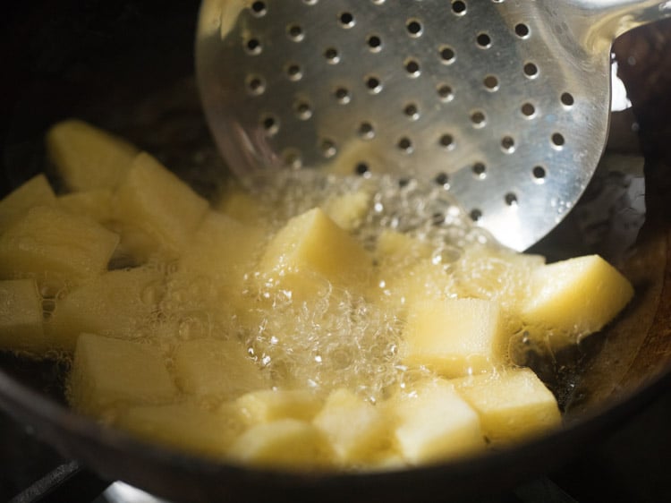 chopped potatoes frying and a slotted spoon