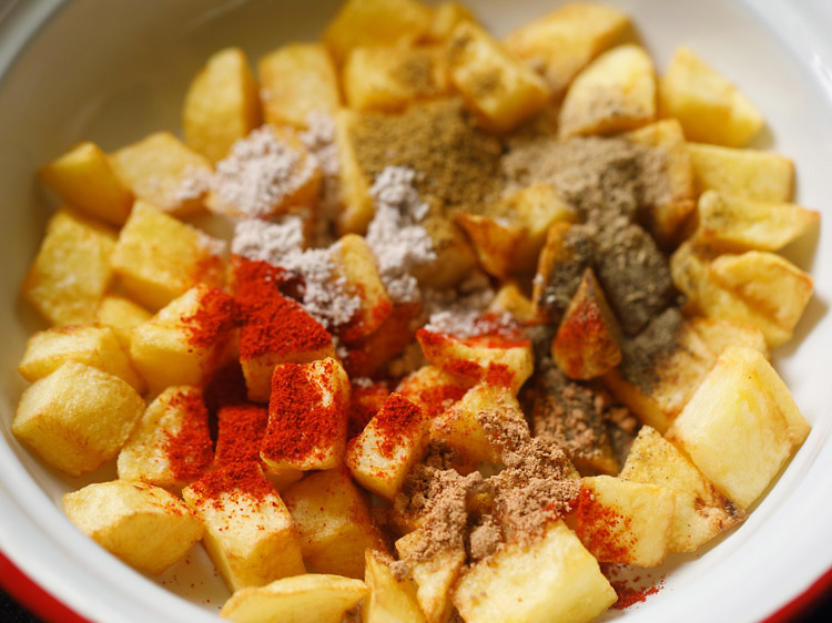 spice powders and salt with cooked hot potato cubes