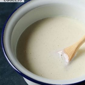 vanilla custard in a white enamelled bowl with wooden spoon inside.