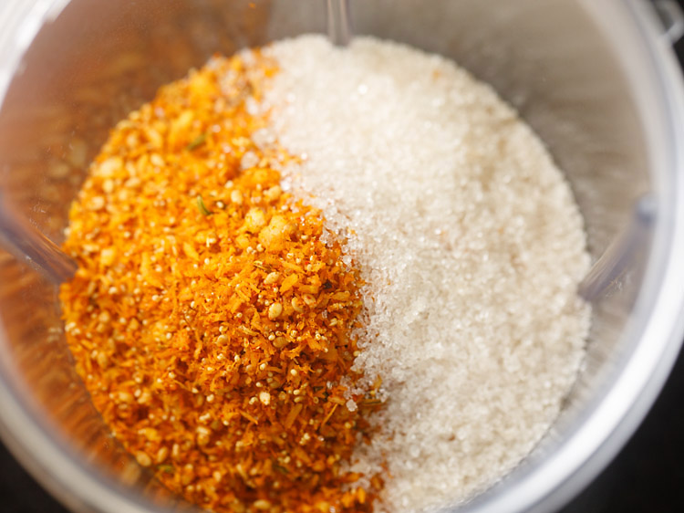 roasted spiced stuffing mixture and sugar added in a grinder jar for making stuffing for bhakarwadi recipe. 