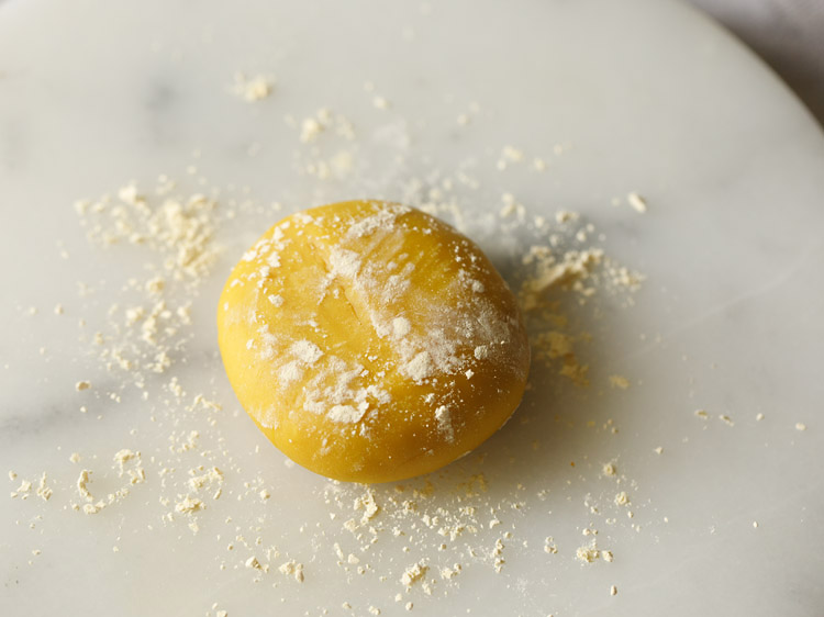 flattened dough portion sprinkled with some besan. 