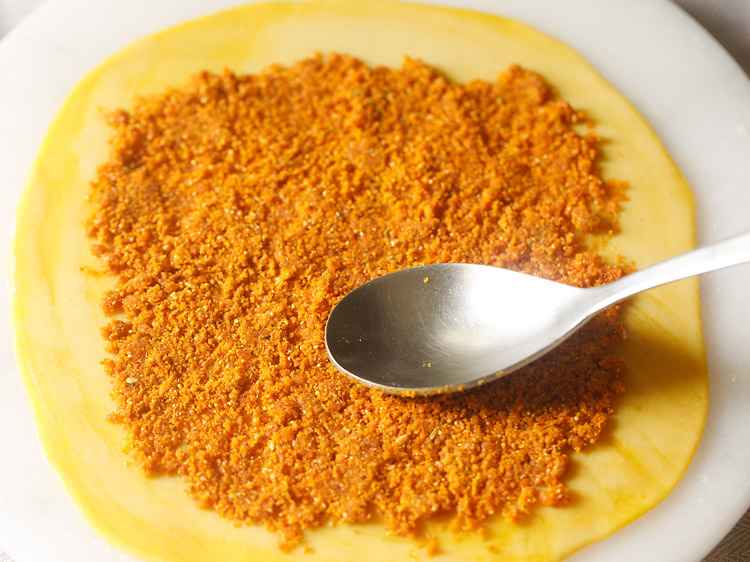 pressing stuffing mixture with a spoon to make bakarwadi. 