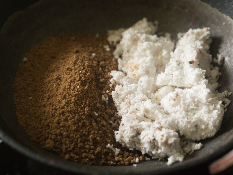 fresh grated coconut and jaggery powder taken in a heavy pan for making kozhukattai recipe.  