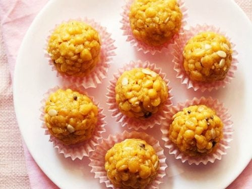 top shot of six boondi laddu in pink muffin liners on a white plate placed on pink napkin