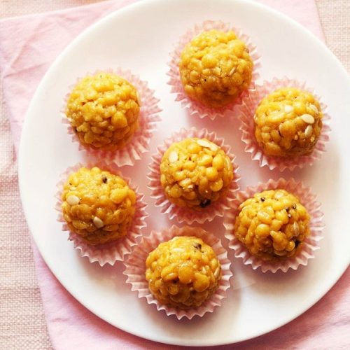 top shot of six boondi laddu in pink muffin liners on a white plate placed on pink napkin