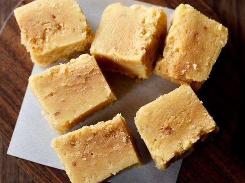 cubes of mysore pak on a wooden serving tray on a table.