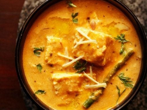 paneer lababdar in a black bowl with ginger juliennes on top.