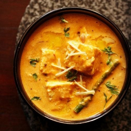 paneer lababdar in a black bowl with ginger juliennes on top.