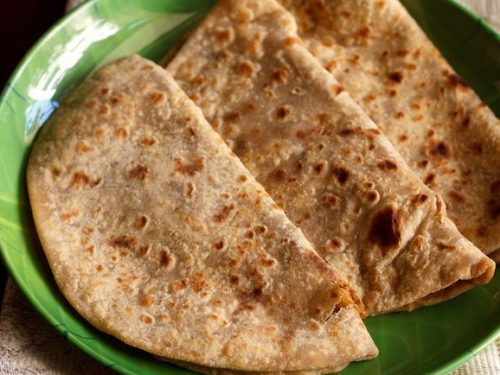 puran poli folded and served on a green color plate.