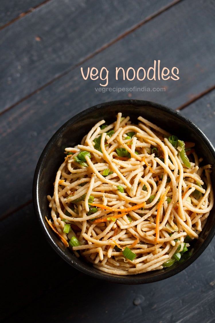 veg noodles served in a black bowl on a dark blue-gray wooden board