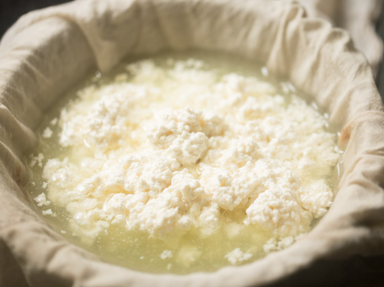 curdled milk with whey in the muslin lined bowl. 