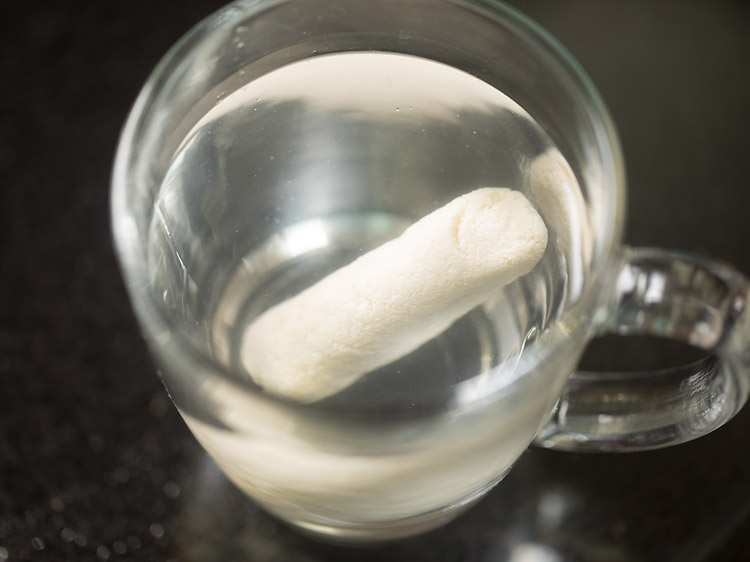 checking whether cham cham sweet is cooked or no by putting it in a mug of water. 