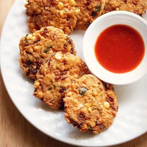 dal vada arranged neatly on a white plate next to a small white bowl of red chutney