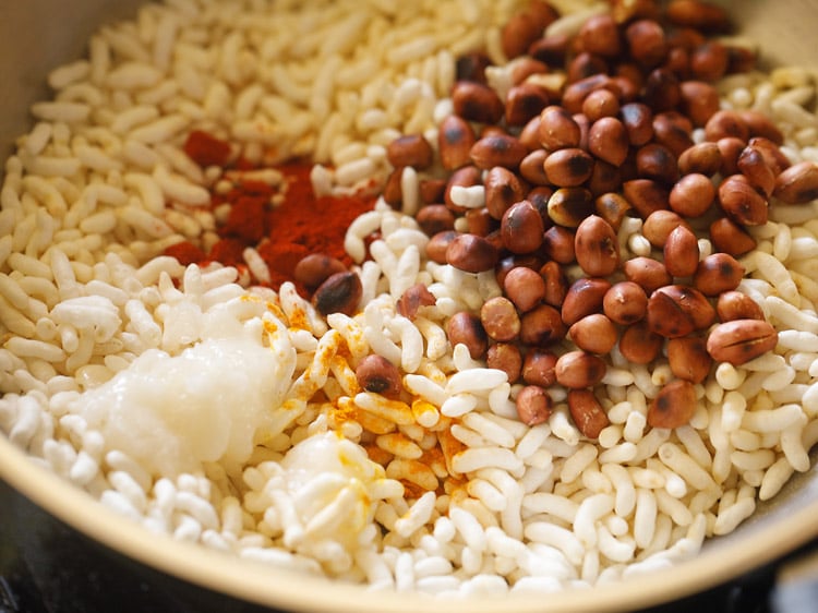 ground spice powders, coconut oil and roasted peanuts added to the roasted puffed rice. 