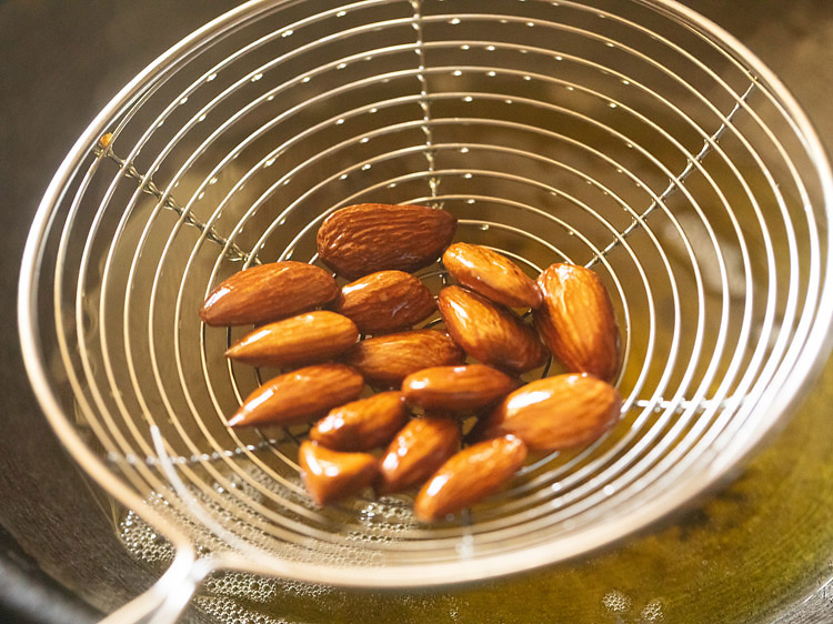 removing fried almonds with a slotted spoon. 