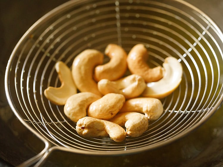 removing fried cashews with a slotted spoon. 