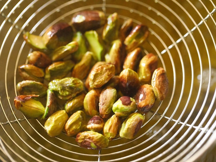 removing fried pistachios with a slotted spoon. 