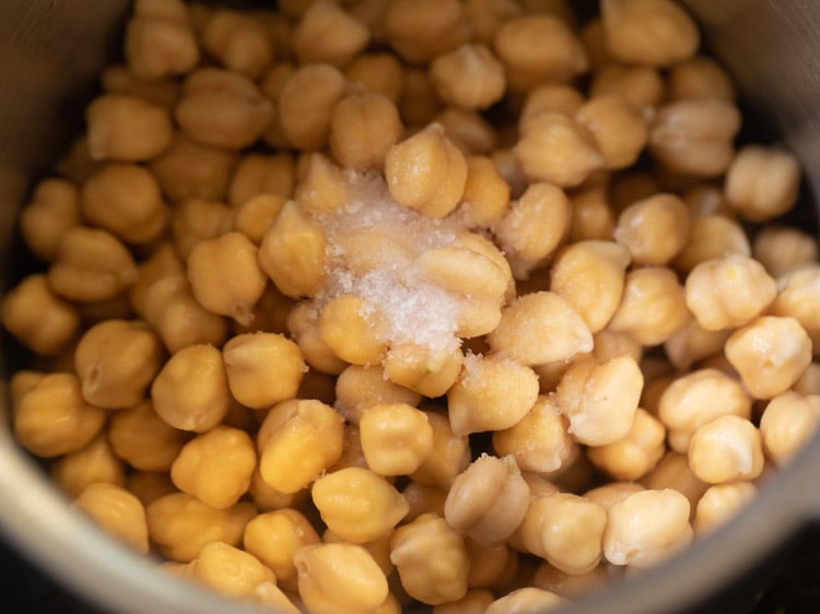 adding chickpeas and salt in the pressure cooker