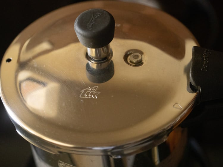 covering pressure cooker tightly with lid and pressure cooking chana