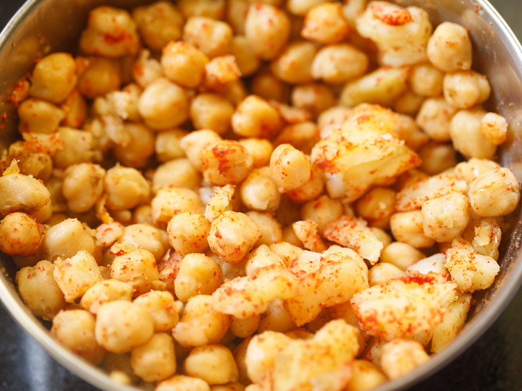 mixing spice powders, salt with chana and potatoes