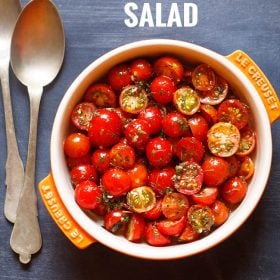 cherry tomato salad in a orange and cream colored flat bowl with text layovers.